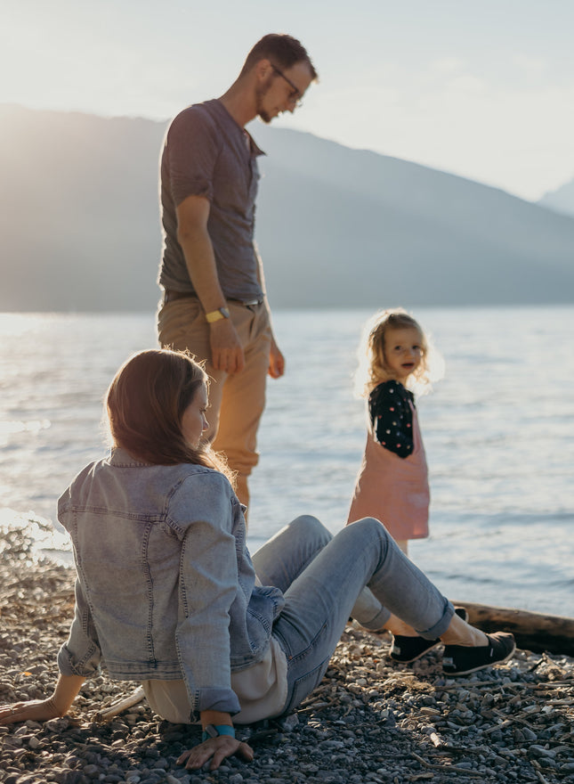 Sunny day with a family sitting on a lake shore, parents and kids are wearing sun-a-wear UV trackers on wristbands