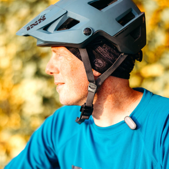 Man wearing UV tracker on his collar while riding a bike on a sunny day